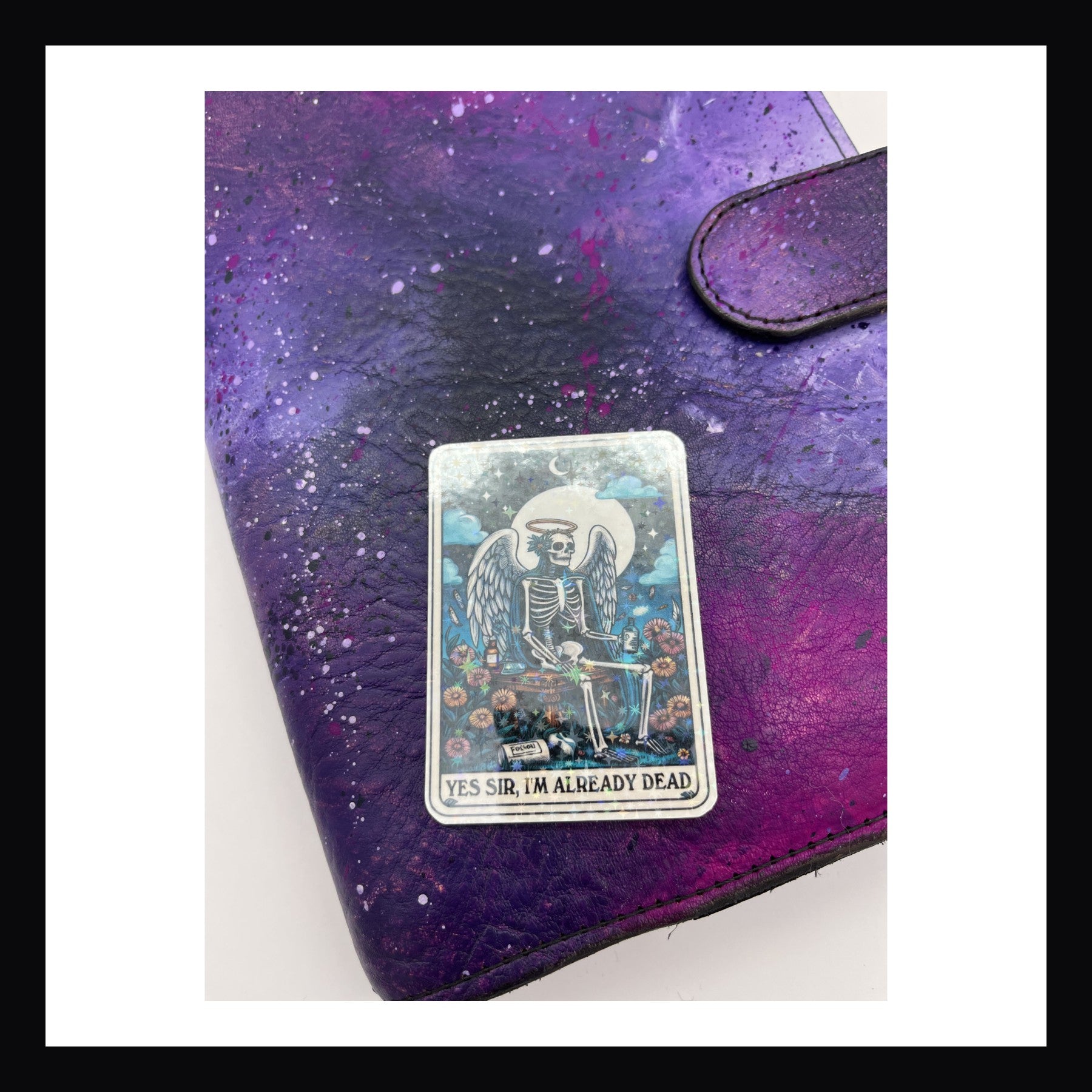 Alternative Tarot Die Cuts - Already Dead is a holographic die cut sticker featuring a skeleton sitting with angel wings and a halo. 