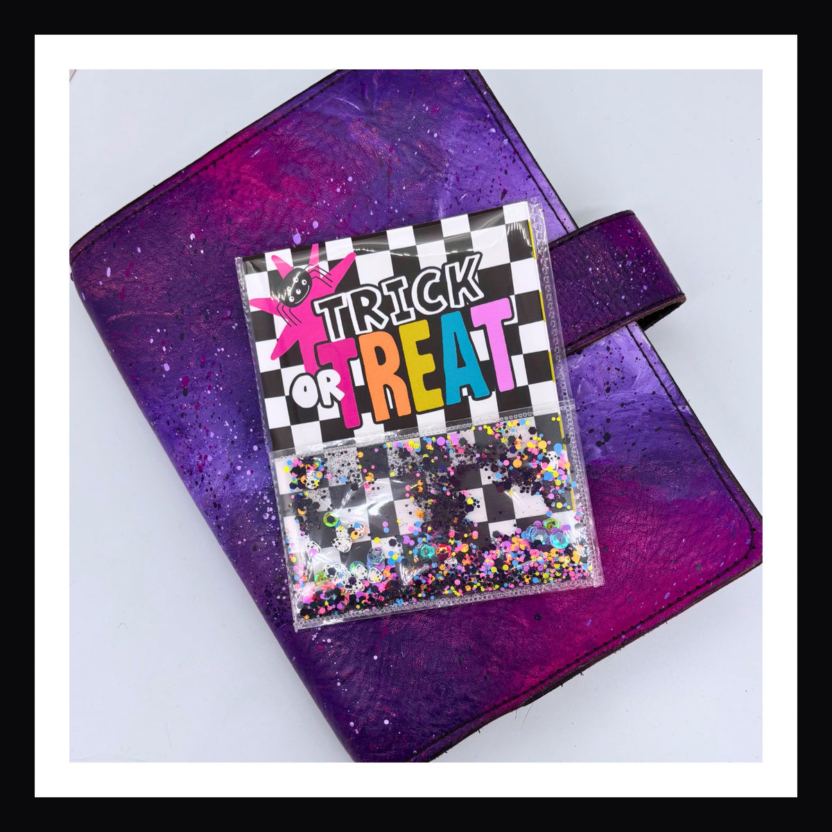 Bright Halloween Shaker Pocket shown on purple planner.  The shaker part is filled with black and neon glitter.  