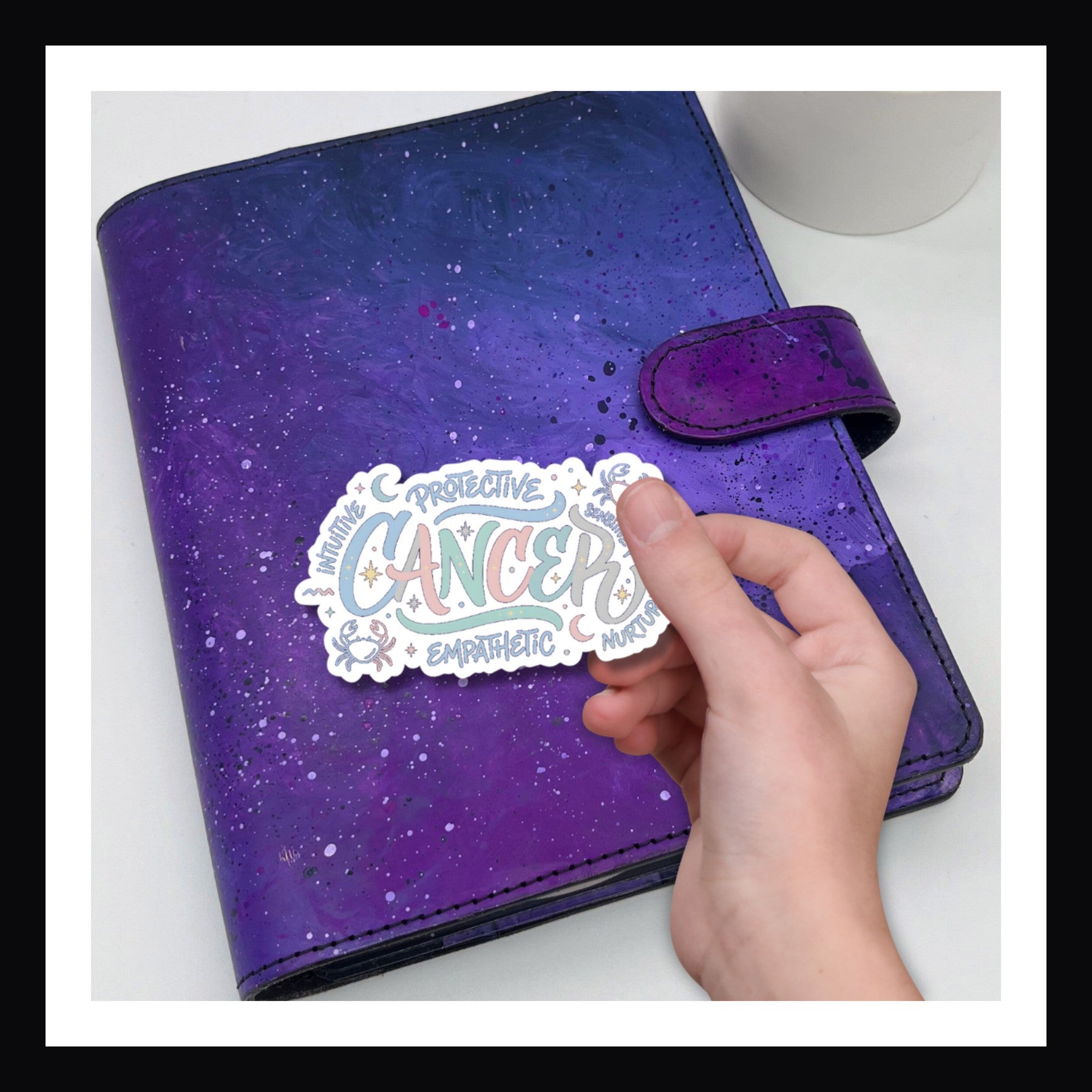 Purple planner with a hand holding a 'Cancer' sticker on a white background