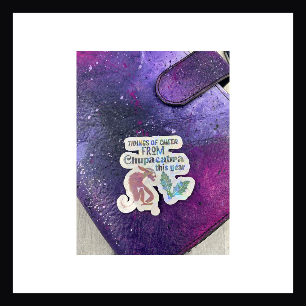 Holographic die cut sticker featuring chupacabra.  "Tidings of cheer from Chupacabra this year"