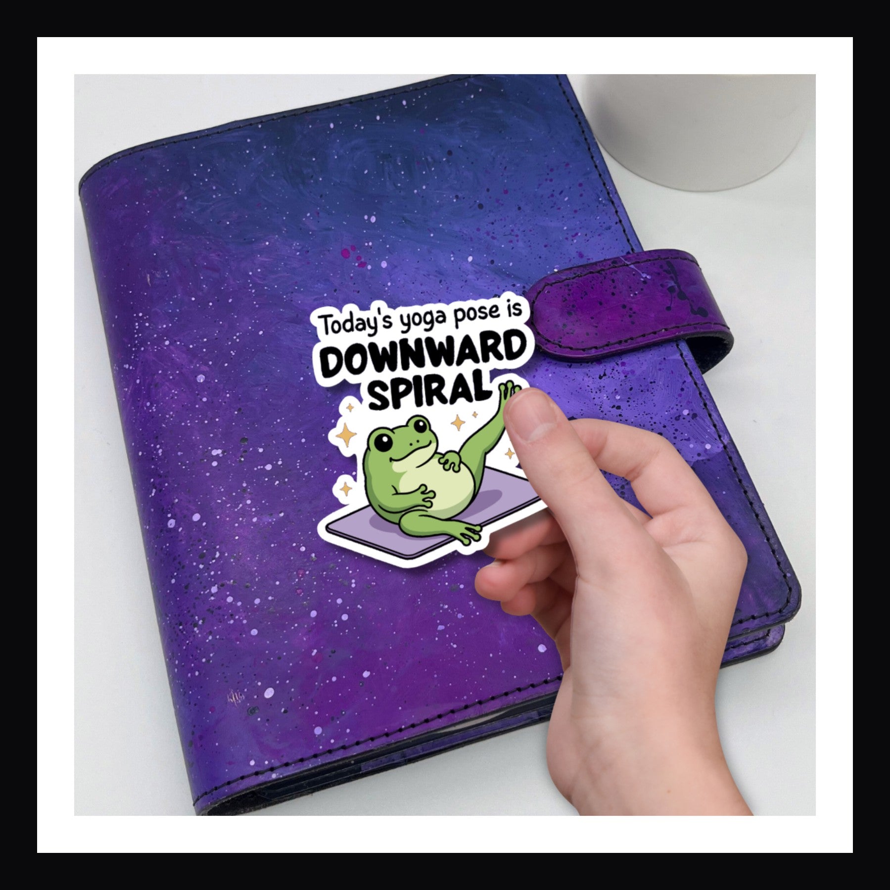 Die Cut Sticker - Downward Spiral.  Frog sticker with saying "Today's yoga pose is downward spiral" shown over a purple planner.