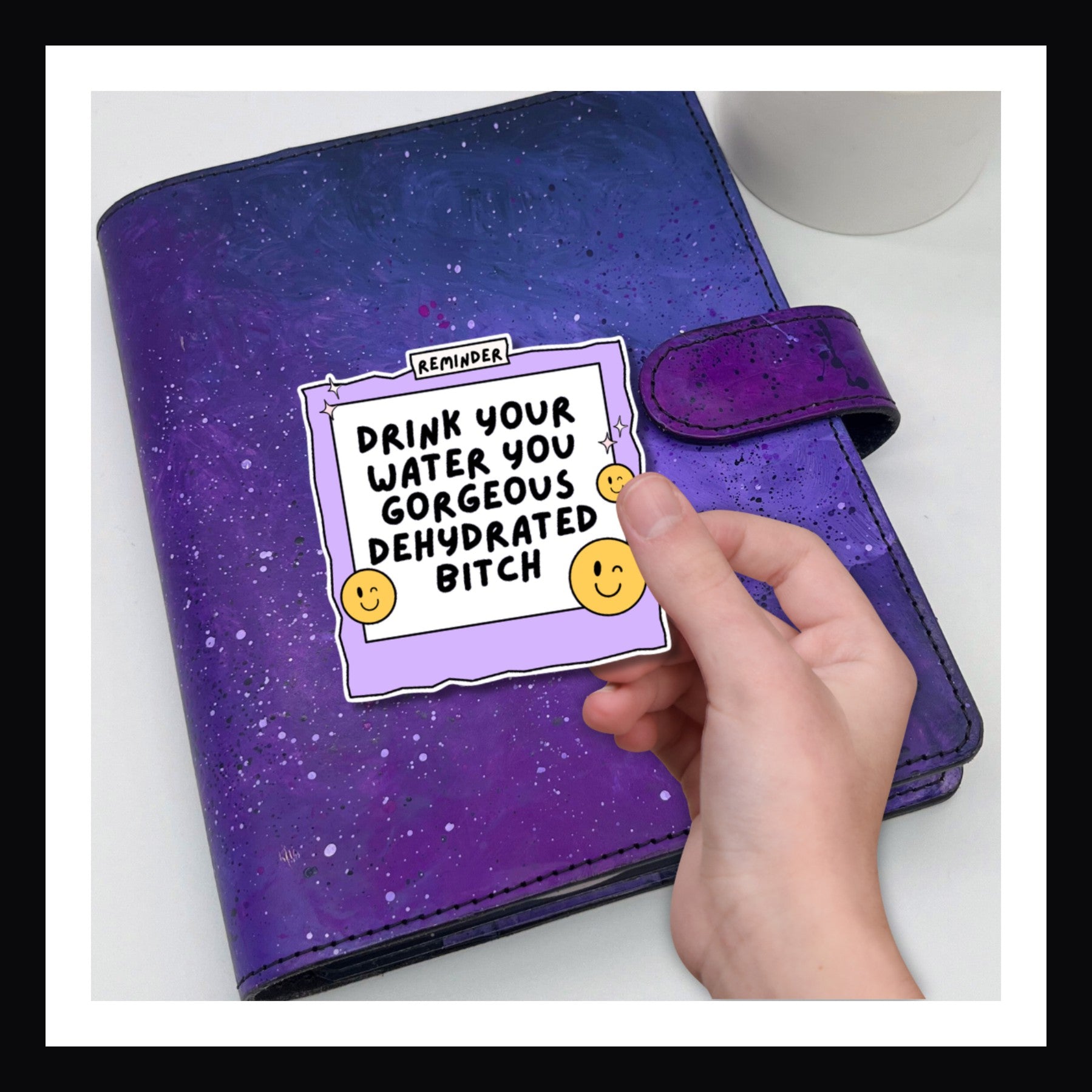 Drink Your Water Die Cut Sticker - purple polaroid shaped sticker reads "Drink your water, you gorgeous dehydrated bitch" shown on a purple planner.