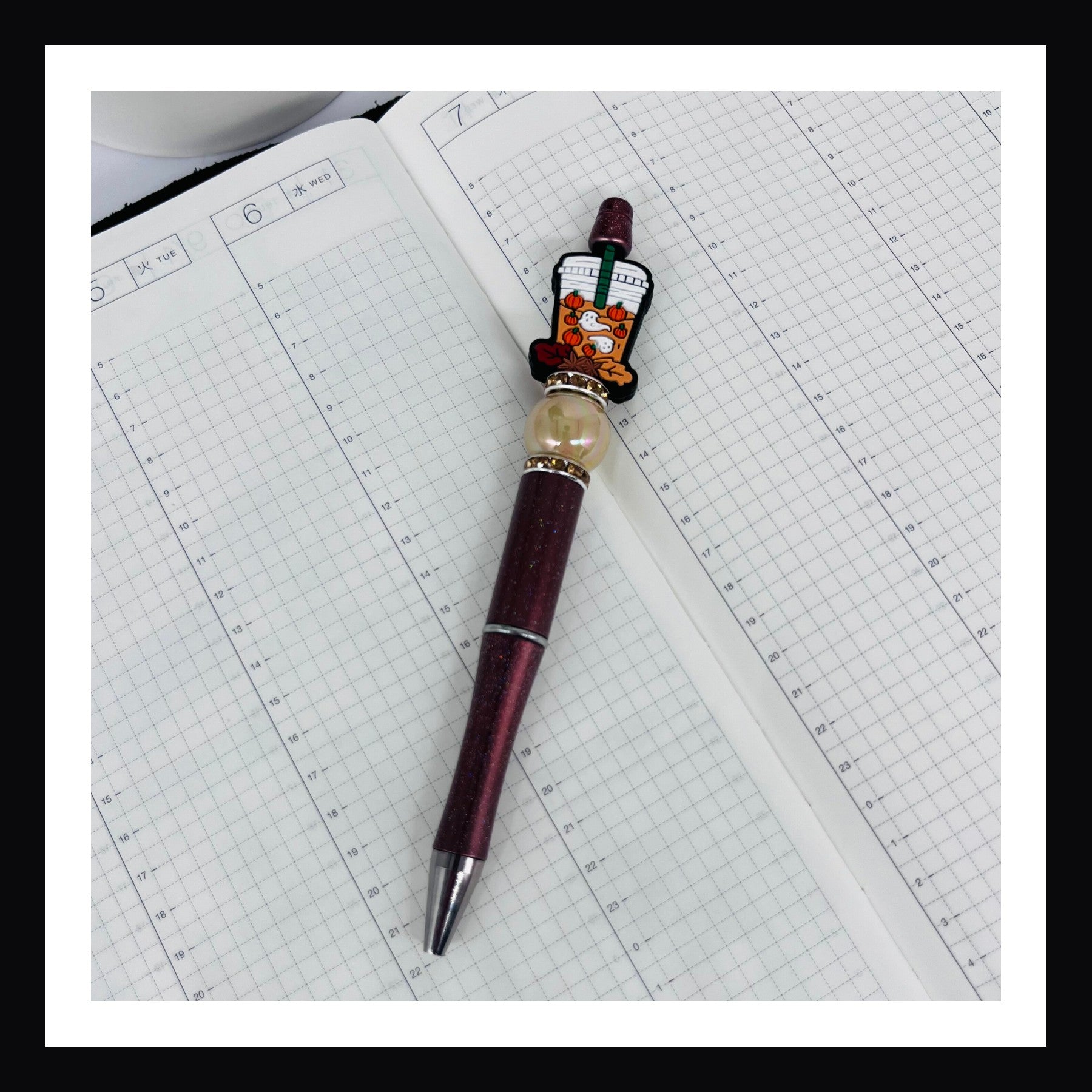 Pumpkin Spice Ghosts Pen is a black ink ballpoint pen.  It features a glittery brown barrel opalescent bead, rhinestone spacers and a silicon bead of a coffee drink with leaves, pumpkins and ghosts. 