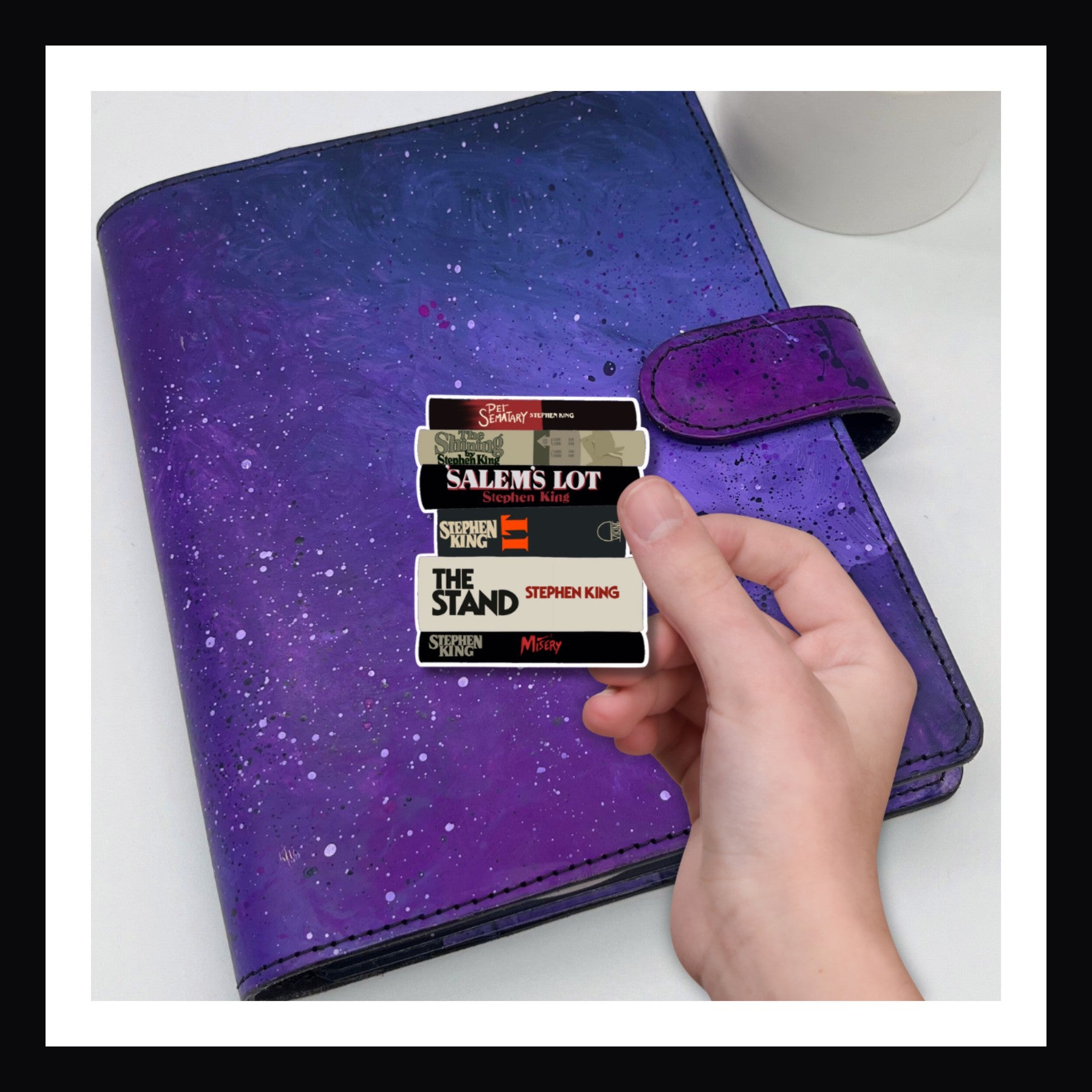 die cut sticker of various Steven King books shown on a purple planner.