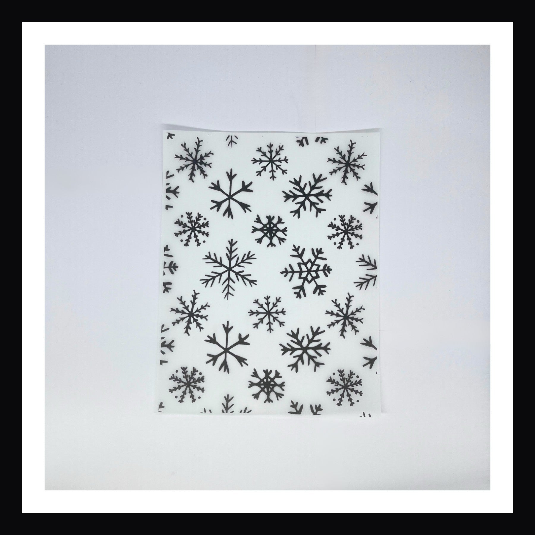 Monochromatic Christmas Vellum in Monochromatic Snowflakes. A 8x10 sheet of printed vellum. This design features a scattering of different snowflakes in various sizes and styles.  Print is black & white.