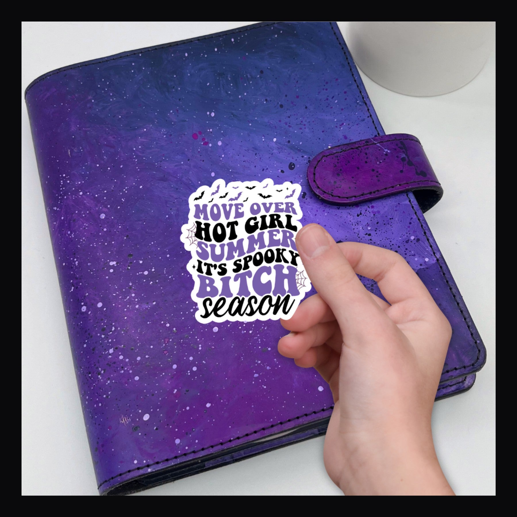 Move Over Die Cut sticker. Says "move over hot girl summer. It's spooky bitch season" in purple and black text. Shown on a purple planner.