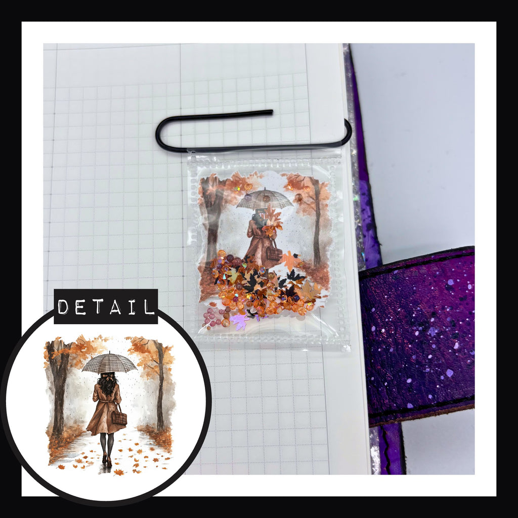 November Rain Shaker Paperclip in Late Autumn Walk features a design of a woman on a walk with an umbrella.  Shaker includes autumn leaf confetti, orange gems and muted brown caviar beads.
