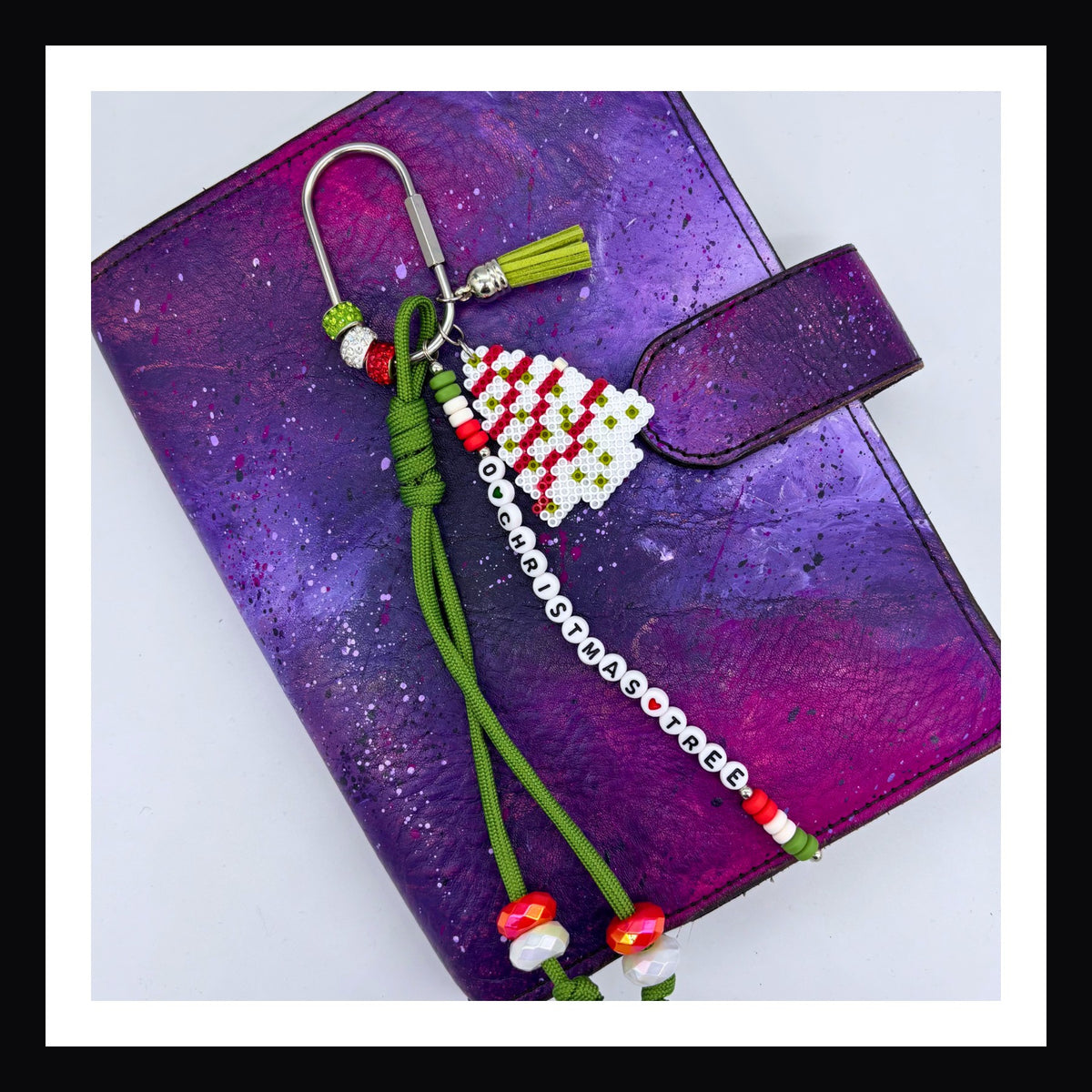 O Christmas Tree Carabiner Charm features a handmade charm that looks like the Christmas tree cake treat. Also includes a beaded tag that spells out "O Christmas Tree", a paracord knot with beads, vegan leather tassel and more beads on the carabiner to add holiday sparkle.  