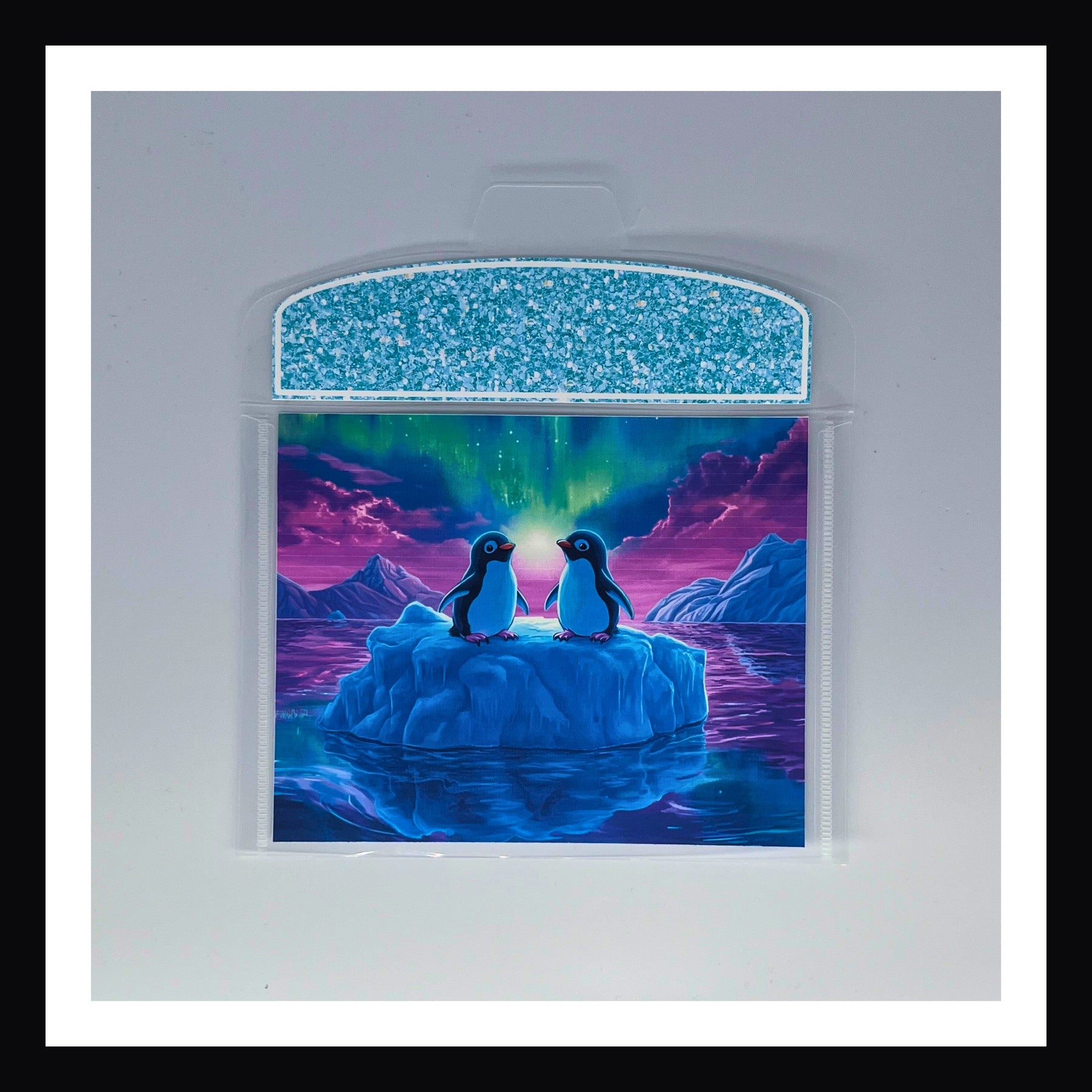 Bright 90s Style Envelope - Penguins features two adorable penguins floating on an ice berg with Aurora Borealis in the background.  Flap color is an electric aqua color. 