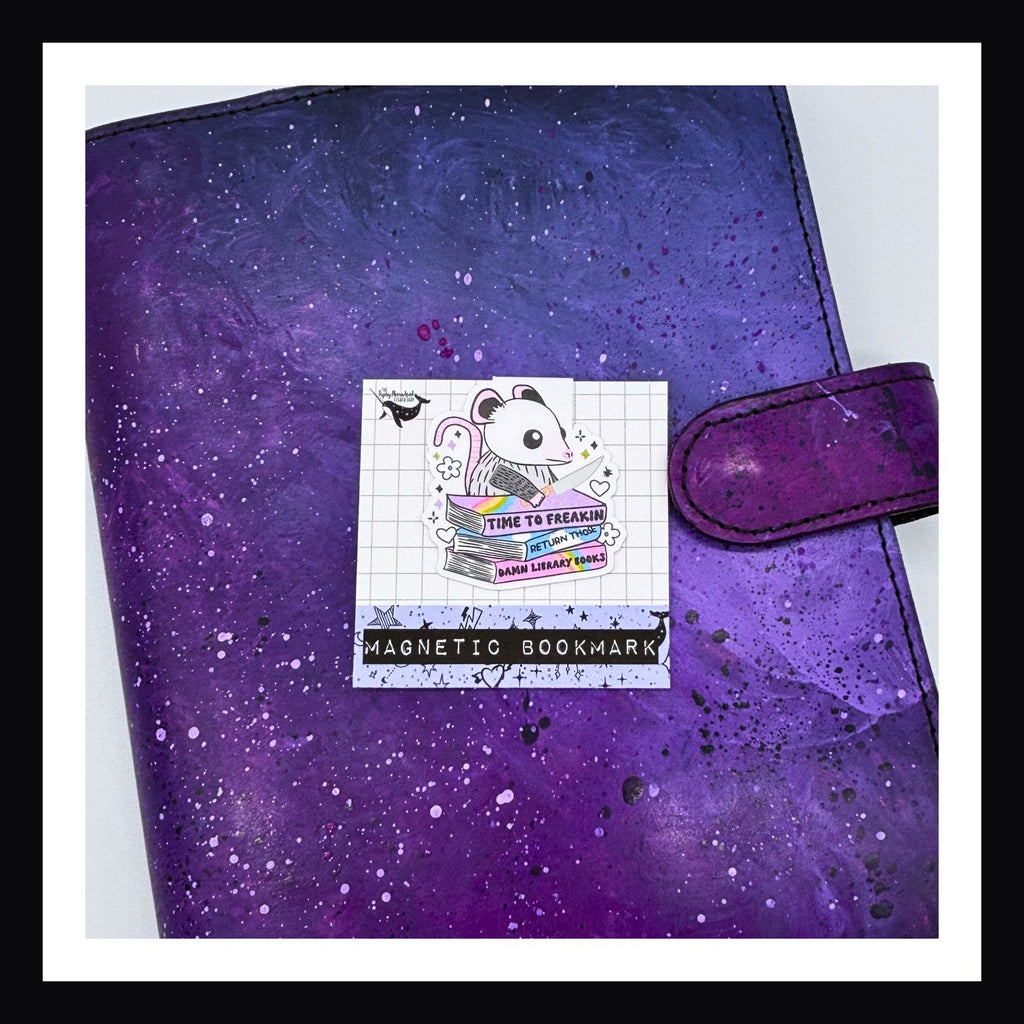 Magnetic Bookmark -Return Your Library Books shown on top of a purple planner.