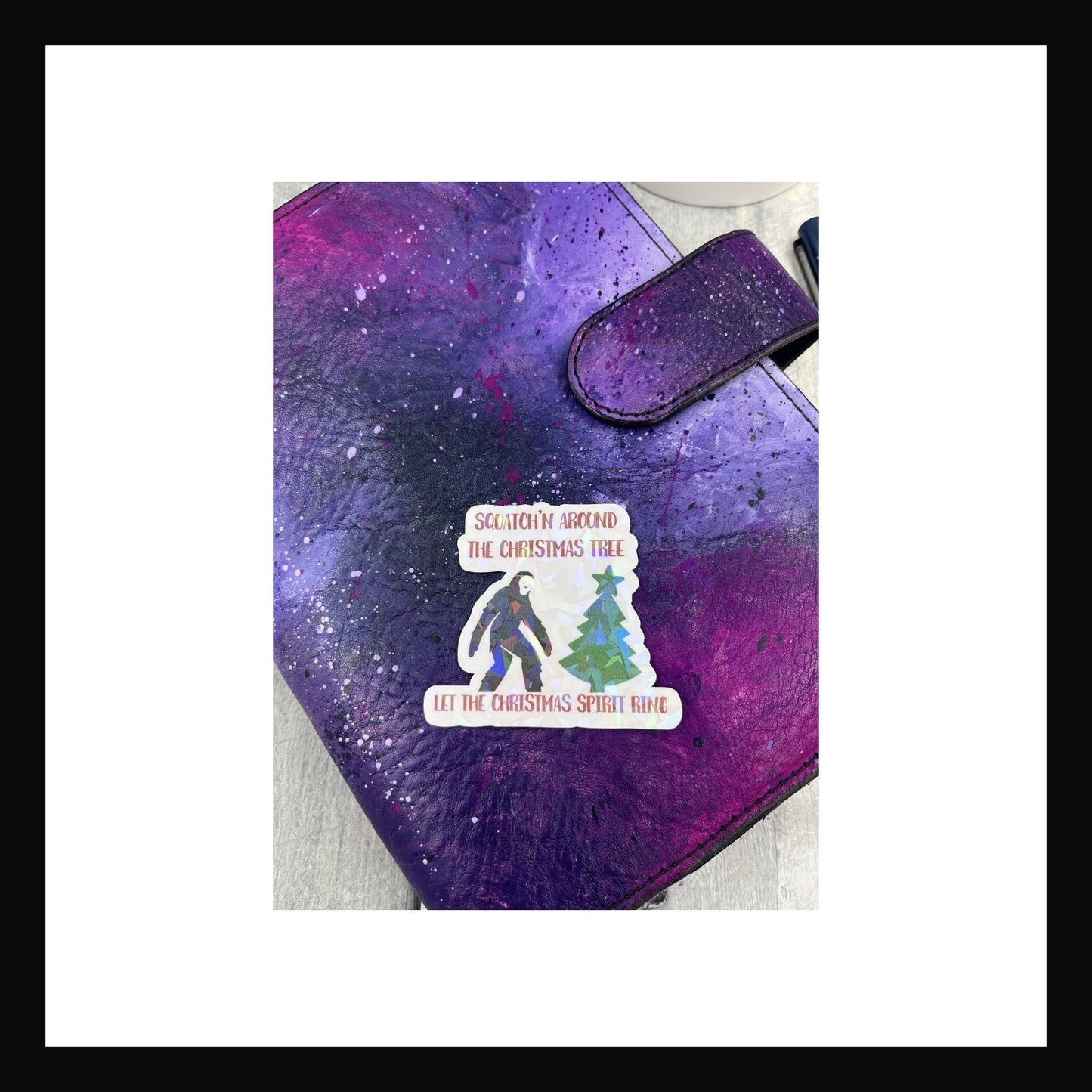 Holographic die cut sticker featuring christmas tree and Sasquatch. "Squatchin' around the christmas tree let the christmas spirit ring"