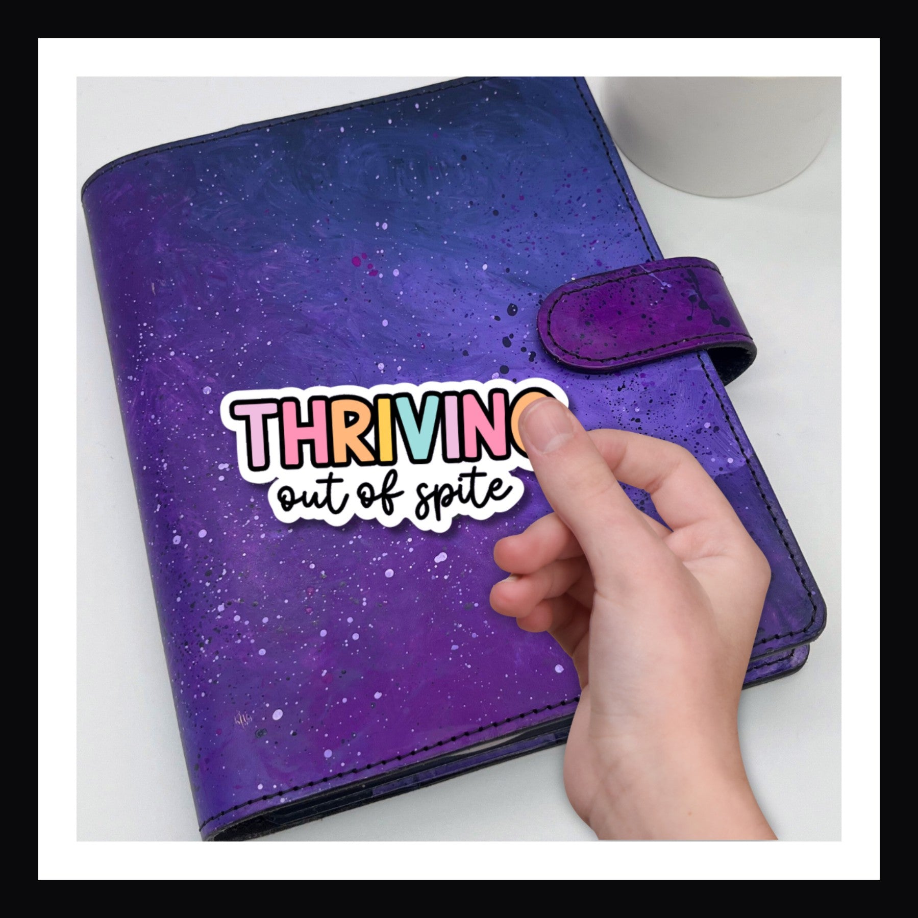 Thriving Out of Spite Die Cut Sticker shown on a purple planner.